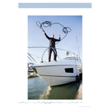 A person on the bow of a motorboat, embodying the teachings of "Motor Boating Basics" by Adlard Coles, skillfully throws a coiled rope into the air. The boat is docked in a marina, where calm water and clear skies provide the perfect backdrop for this dynamic moment in nautical navigation.