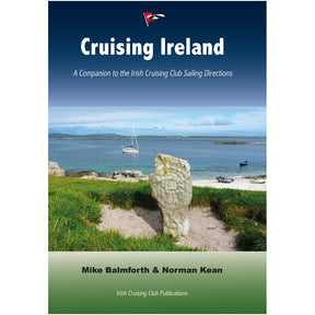 Cover of "Cruising Ireland" by the Irish Cruising Club features a coastal scene with a sailboat, beach, and grassy shore, evoking the nautical past. A stone marker stands in front under a blue sky with clouds.