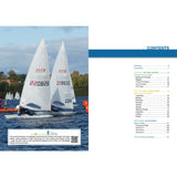 Two ILCA dinghy sailboats with sail numbers 220826 and 219655 race on a lake under a clear sky, their impressive techniques mirrored in the water below. To the right, "The ILCA Book" by Fernhurst Books shows its contents page filled with racing strategies.