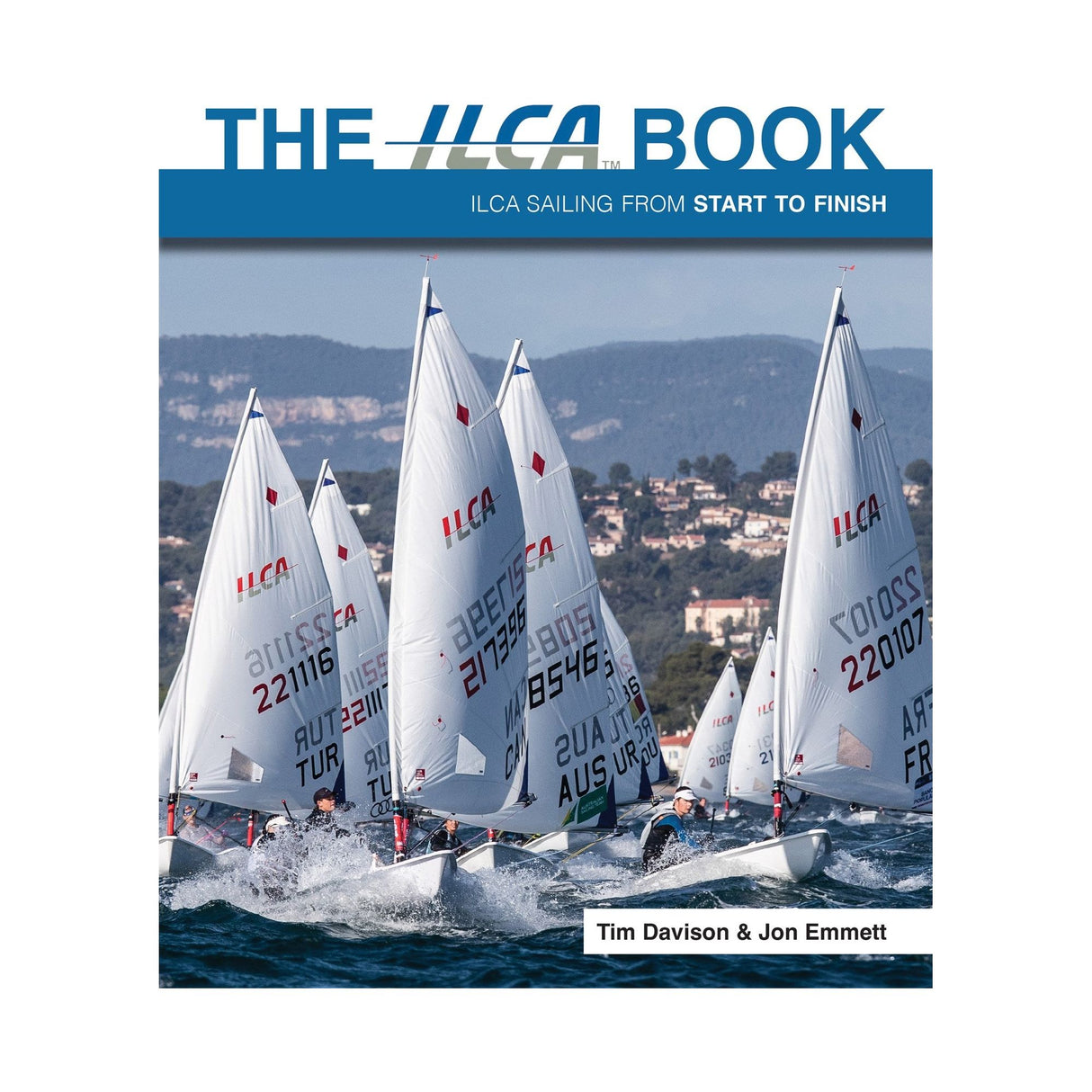 Cover of "The ILCA Book" by Fernhurst Books, authored by Tim Davison and Jon Emmett. It features several ILCA dinghy sailboats with their sails billowing as they glide across the water against a picturesque backdrop of hills and buildings, providing insights into sailing techniques and racing strategies.