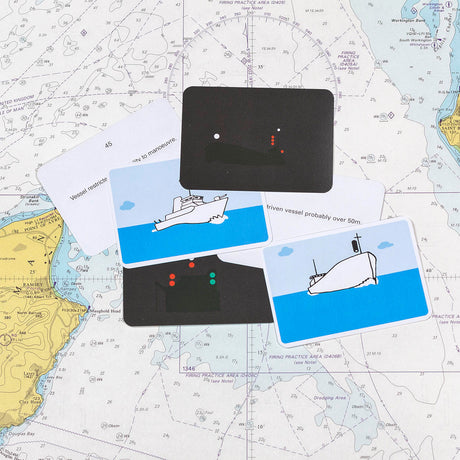 Flip Cards' Sailor Essentials Set features nautical cards adorned with ship images and navigation lights, beautifully displayed against a marine chart backdrop. The chart is filled with intricate navigational markings and includes a lively map section, capturing the essence of sailing.