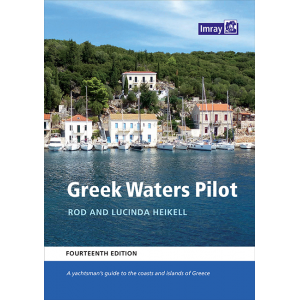 Book cover of the "Greek Waters Pilot" by Rod and Lucinda Heikell, fourteenth edition, published by Imray. The cover features a scenic view of a coastal village with sailboats anchored by the shore and a green hillside in the background. This cruising guide is essential for yachting in Greece.