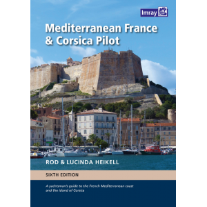 The book cover of Imray's "Mediterranean France & Corsica Pilot" showcases an image of coastal buildings and boats docked at a marina, with a historic fortress on a hill in the background. Set against the picturesque Côte d’Azur, this sixth edition is authored by Rod & Lucinda Heikell.