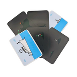 A collection of Flip Cards: Lights and Shapes is arranged on the table. Most cards display a dark background with small dots, but one features a minimalist illustration of an airplane against a blue sky with a cloud, evoking the image of navigation lights guiding mariners across the vast expanse.